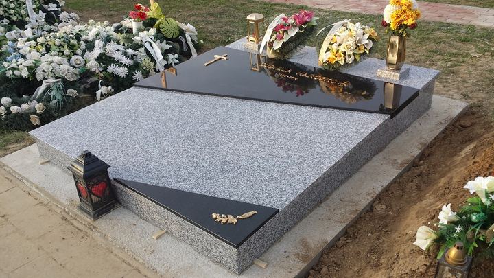 Dvojfarebný žulový hrob s asymetrickým detailom a zlatým ornamentom.
