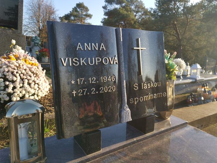 Pomník v tvare otvorenej knihy z tmavej žuly so svetlým písmom a krížom.